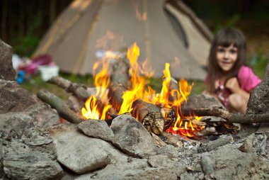 Kız ateşin yanında oturuyor. Yüksek ısıya duyarlı. Çadırdaki bebek.