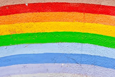 Eski, kirli, çatallı beton duvar. Gökkuşağının farklı renkleri. Duvardaki boyalarla boyanmış gökkuşağı.