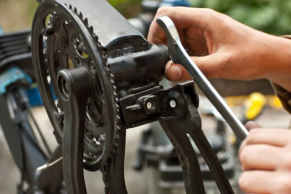 Masters repair the bicycle. Tools in hands close up.
