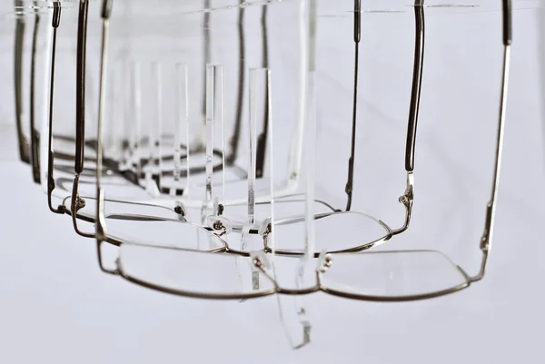 许多白色背景的眼镜 玻璃杯堆放在一个透明的商店橱窗上的一排 玻璃立在灰色的桌子上 光学的销售和展览 — 图库照片