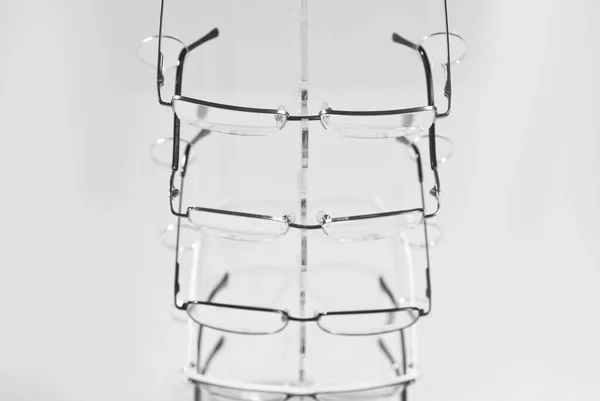 许多白色背景的眼镜 玻璃杯堆放在一个透明的商店橱窗上的一排 玻璃立在灰色的桌子上 光学的销售和展览 — 图库照片