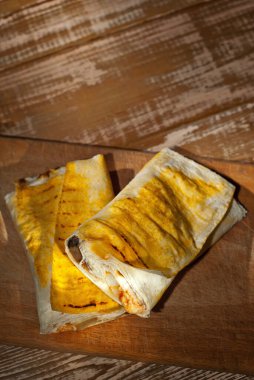 Sarı shawarma ikiye bölünmüş. Pembe pejmürde bir arka planda Pita ekmeği. Eski bir tahta üzerinde yemek..