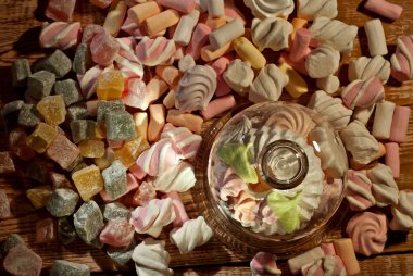 Tahta bir masada, bardaktaki şekerler. Eski püskü bir tahta üzerinde şeffaf mutfak aletleri ve marşmelovlar. Beyaz yumuşak şekerli pembe yakın çekim.