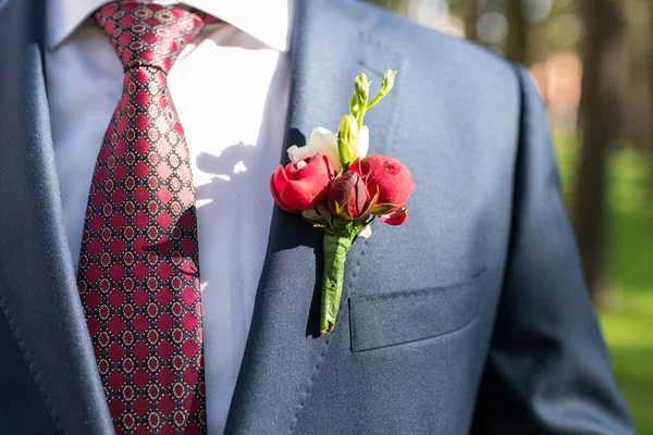 Elegante novio de chaqueta azul, camisa blanca y corbata roja con boutonniere — Foto de Stock