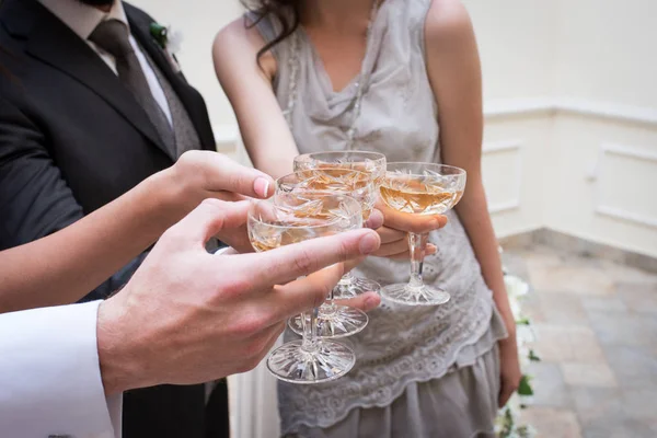 Champagne glasses. Wedding guests clinking champagne glasses with the newlyweds. — Stock Photo, Image