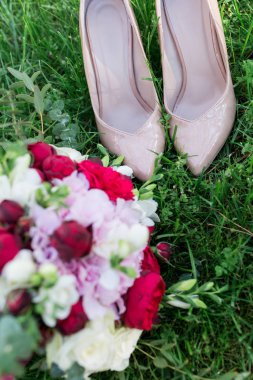 Zarif gelin ayakkabıları ve düğün buket bir çim üzerinde yalan