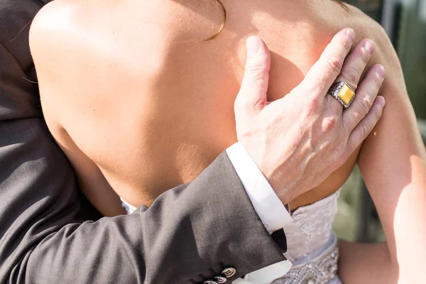 Рука жениха с кольцом из желтого камня на плече невесты — стоковое фото