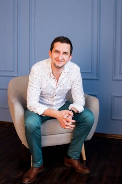 Beyaz gömlek ve yeşil pantolon koltukta oturan mutlu yakışıklı adam