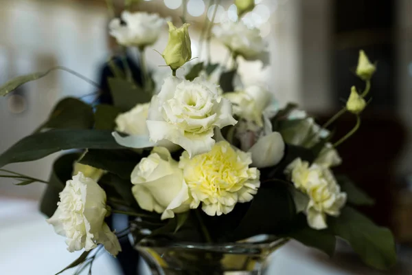 Wedding arrangement with white roses, carnation, and greenery
