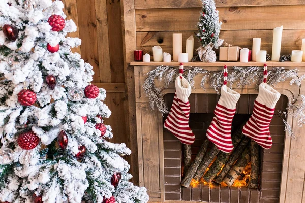 Three New Year\'s boots hanging near the fireplace near the Christmas tree