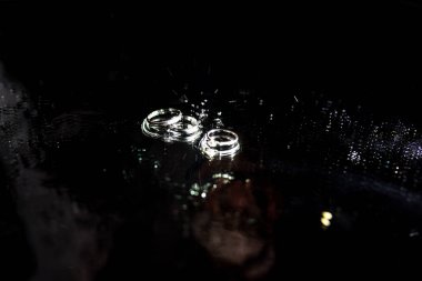 Gelin ve Damat Düğün günü evlilik yüzüğü. Alyans Su damlacıkları karanlık bir arka plan ile