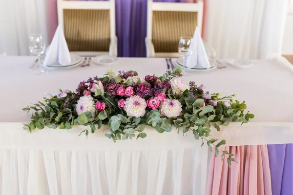 Beautiful pink and creamy flowers on table of newlyweds at wedding reception in restaurant, free space. Wedding table decorated with flowers, served for two people. Wedding table decoration newlyweds.