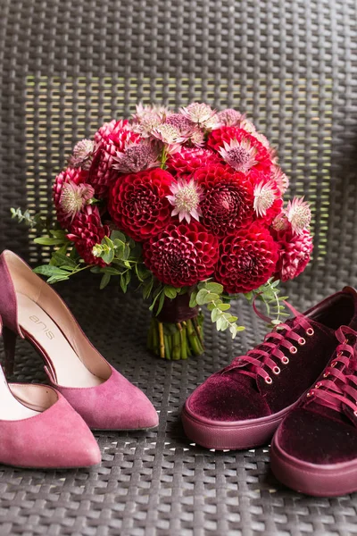 Wedding Heels VS bridal sneakers. Red wedding bridal accessories: bridal heels and sneakers of marsala color, red bridal bouquet from dahlias. Wedding details.