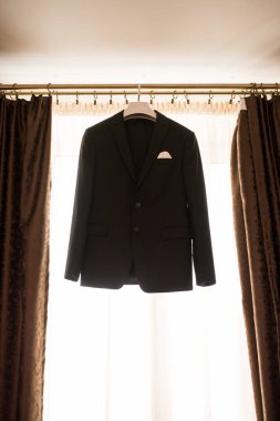 Güzel siyah damat ceket pencere sabah düğün hazırlığı için asılı. Damat aksesuarları