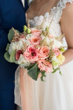 Elleri ile turuncu gül buket düğün gelin tutar. Gelin buketi pastel şekillerde. Çiçekler