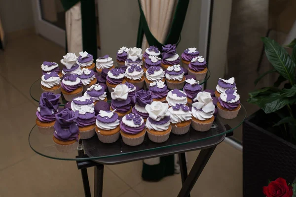 Muffins with cream, wedding sweet table. Purple and white cupcakes. Set of cupcakes. Colorful cream muffins. Catering