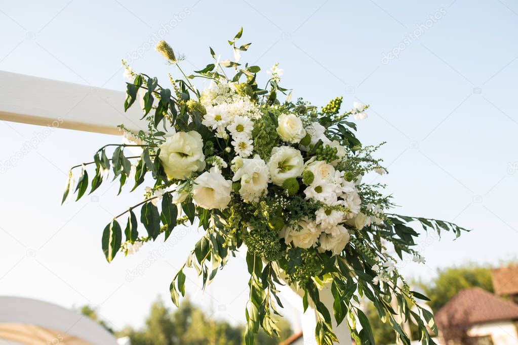 A part of beautiful wedding arch with fresh white flowers and greenery in the garden