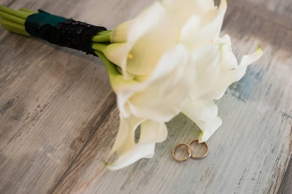 Δύο Χρυσά Δαχτυλίδια Στο Ξύλινο Φόντο Κοντά Άσπρο Γαμήλιο Μπουκέτο — Φωτογραφία Αρχείου