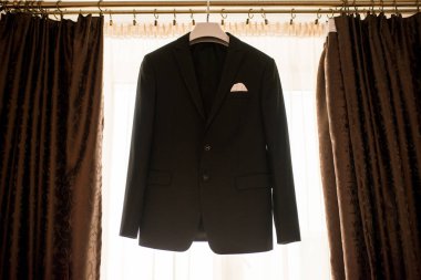 Güzel siyah damat ceket pencere sabah düğün hazırlığı için asılı. Damat aksesuarları