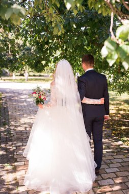 Mutlu gelin ve damadın birbirleri etrafında tutarak ve düğün gününde doğada yürüyüş. Beyaz elbise ve damat gelinin kendi geleceklerini karşılamak için gidiyoruz şefkatle birbirlerine kucaklayan. 