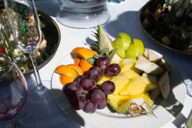 Bir tepsi üzüm, elma, portakal ve masanın üzerinde başka bir meyve. Meyve