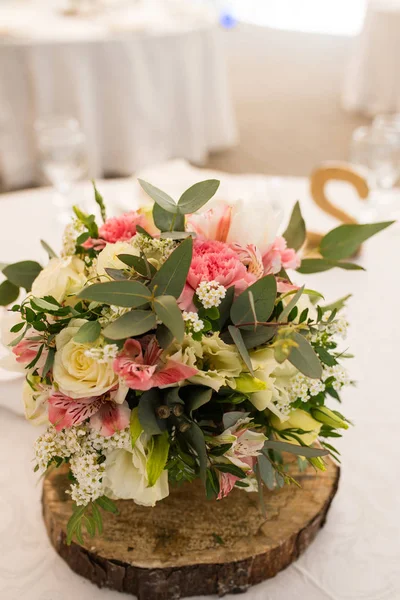 Rustic flower arrangement with white and pink flowers at a wedding banquet. Table set for an event party or wedding reception.