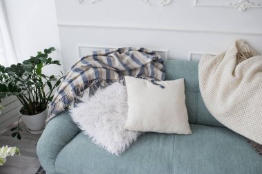 İki dekoratif yastık ve yatak örtüleri mavi kanepede yalan. Rahat ev