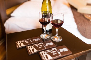 İki kadeh kırmızı şarap ile doldurulur. Bir şişe şarap ve bir kaç çikolata yalan kadehlerin stand. 