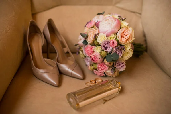 stock image Wedding bouquet with pink peony, yellow roses and greenery with elegant bridal shoes, wedding rings and perfume. Wedding details