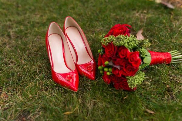 Damenmode Rote Hochzeitsschuhe Mit Goldenen Ringen Fokus Und Brautstrauß Mit Stockbild