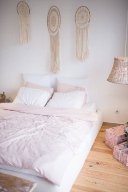 Rüya yakalayıcılarla dekore edilmiş bir odada pembe ve beyaz pamuklu yatak.