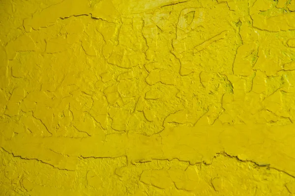 Abstract yellow solid background with cracks in the paint. Texture. A horizontal frame.