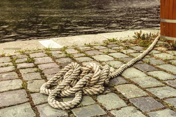 Marine rope tied knot lying on the sidewalk near the pier.