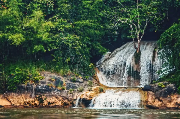 Deep forest waterfall in the wild tropical forest. The shoreline of the river.