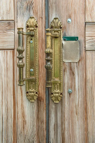 Vintage handles on the old textured wooden door.