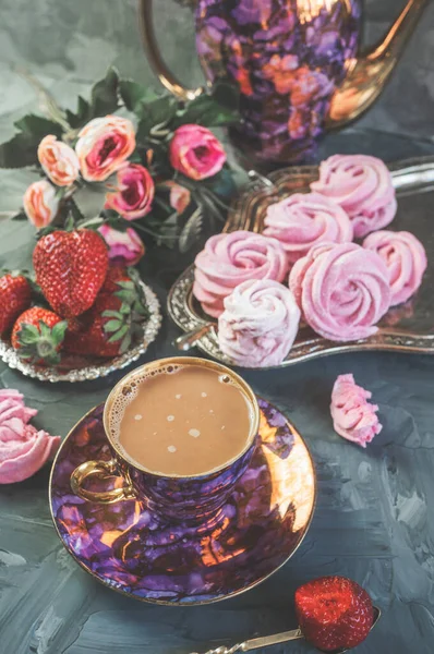 Hot cocoa and chocolate drink in a beautiful silver Cup with pink homemade fruit marshmallows on the table.