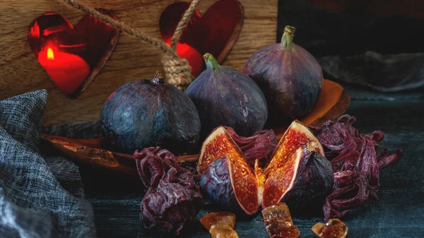 A juicy slice of Fig and a group of figs with lavender on a rustic blue wooden table close-up in a restrained key.