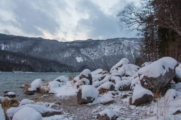 Piedras en la orilla del lago Eibsee con montañas en el fondo en invierno. Baviera. Alemania . — Foto de Stock