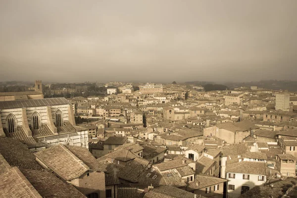 Cityscape of Siena with thick fog on background. Tuscany, Italy. Old polar effect. — Stock Photo, Image