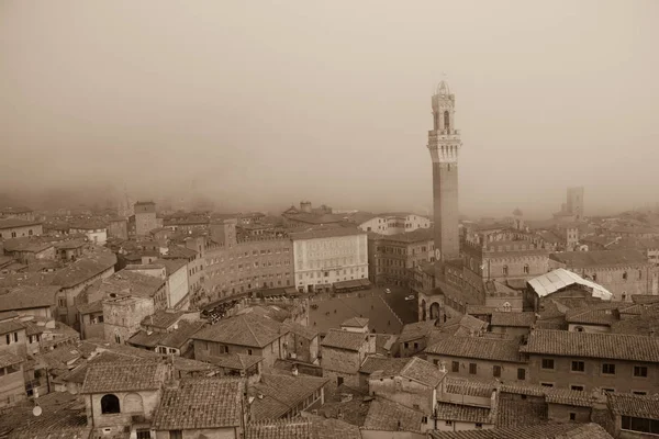 Torre del Mangia sur la Piazza del Campo et les toits tupiques de Sienne dans le brouillard épais. Toscane, Italie. Vieil effet polaire . — Photo