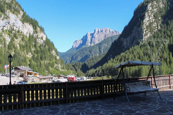 Terrazza con altalene portico in legno. Montagne, foresta verde e cielo azzurro sullo sfondo. Malga Ciapela, Veneto, Italia . — Foto Stock