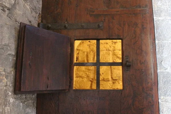 An open window with iron grid of an ancient door of a prison or a dungeon. — Stock Photo, Image