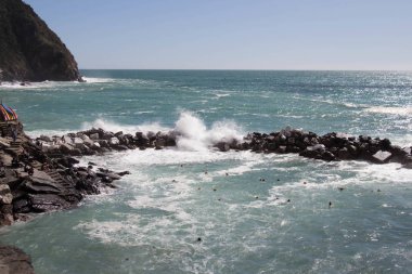 Ufuk çizgisi denizin üzerinde ve dalgalar taşlara çarpıyor..