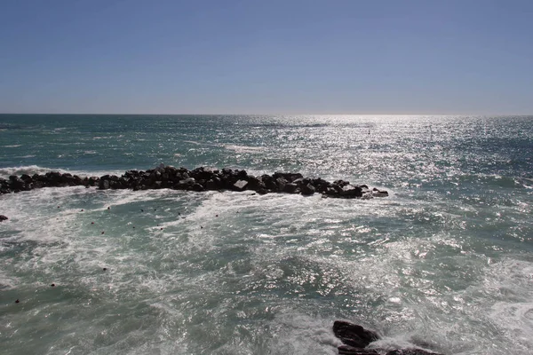 Horizon line over sea and a waves are crashing stones.