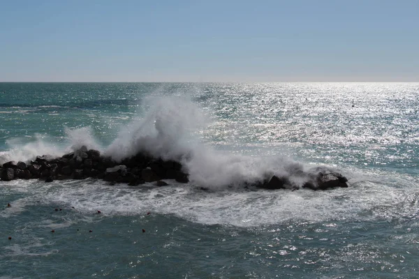 Horizonte línea sobre el mar y una ola está rompiendo piedras . — Foto de Stock