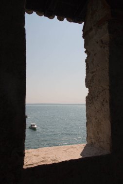 Eski ortaçağ penceresinden deniz ve ufuk çizgisi manzarası.