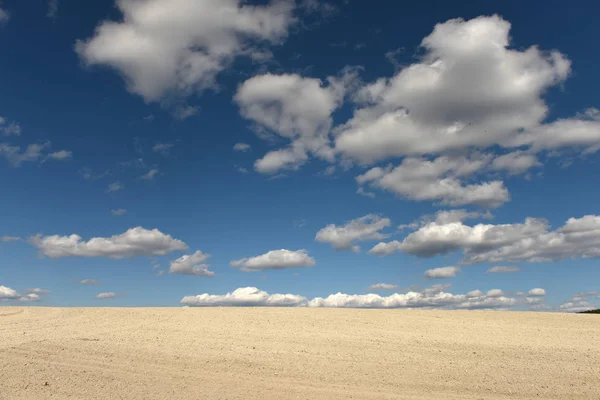 Clay land and white clouds on the blue sky — Stock Photo, Image