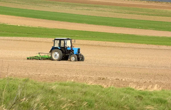 Traktor bei der Arbeit bei der Bearbeitung eines Feldes im Frühjahr, Ackerland, gepflügt — Stockfoto