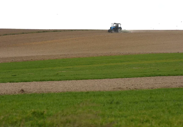Traktor bei der Arbeit bei der Bearbeitung eines Feldes im Frühjahr, Ackerland, gepflügt — Stockfoto