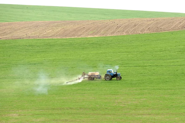 tractor spraying the chemicals on the green field